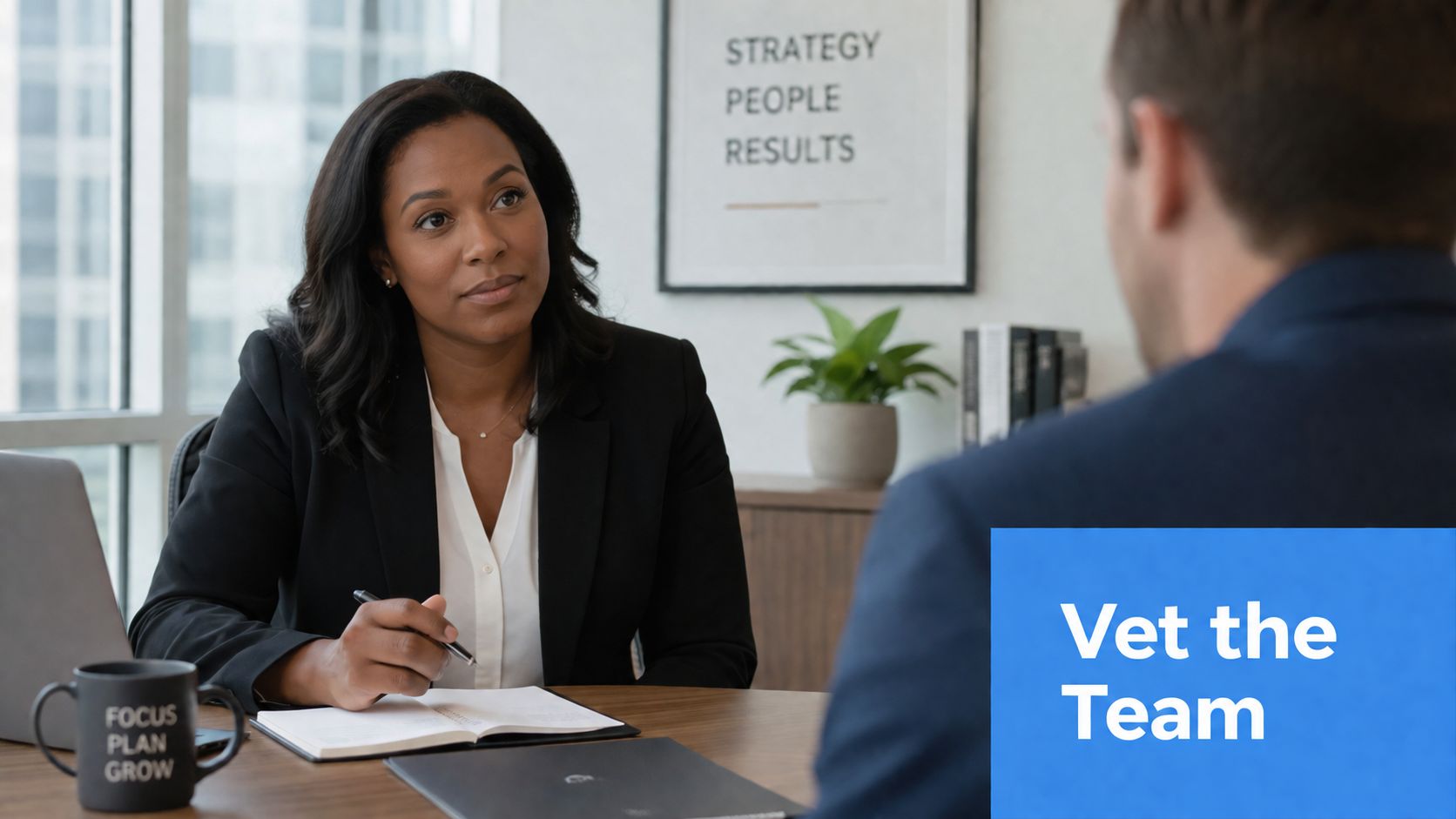 A professional woman in a business suit interviews a candidate for a role during a meeting.